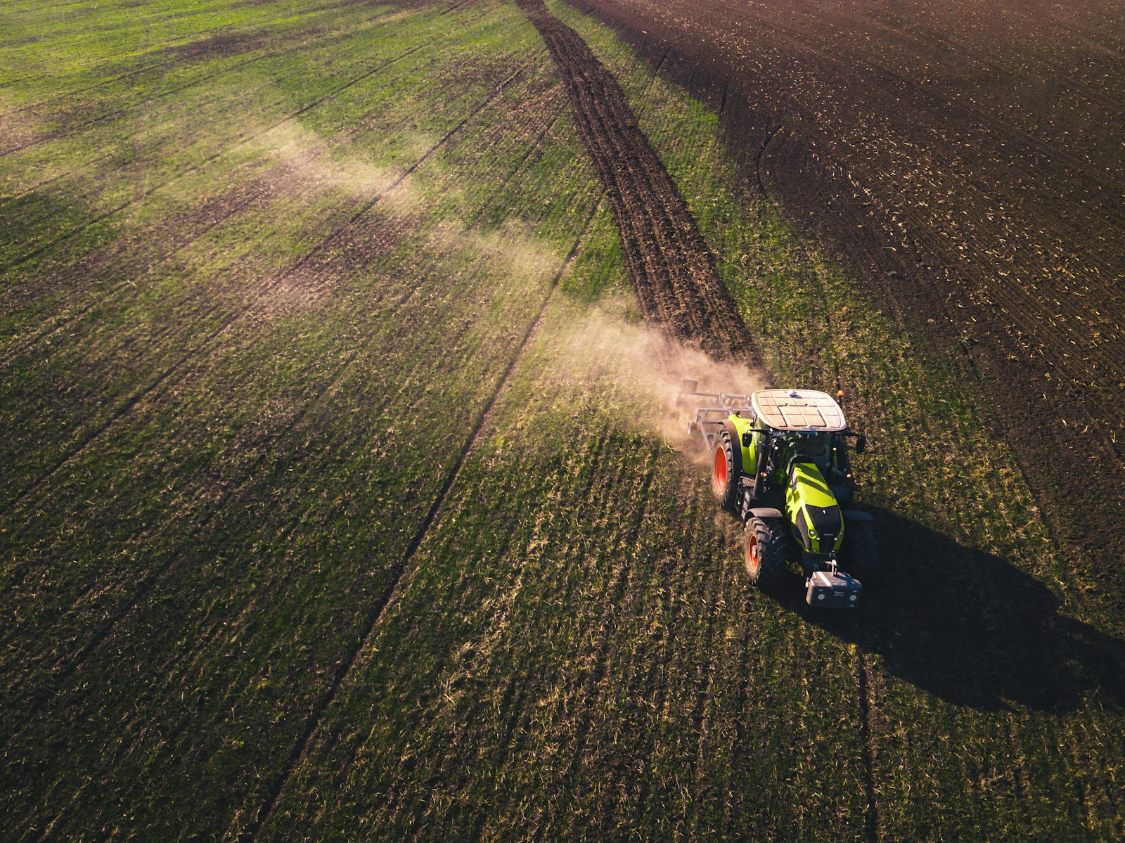 A tractor working a wide green field, seen from above